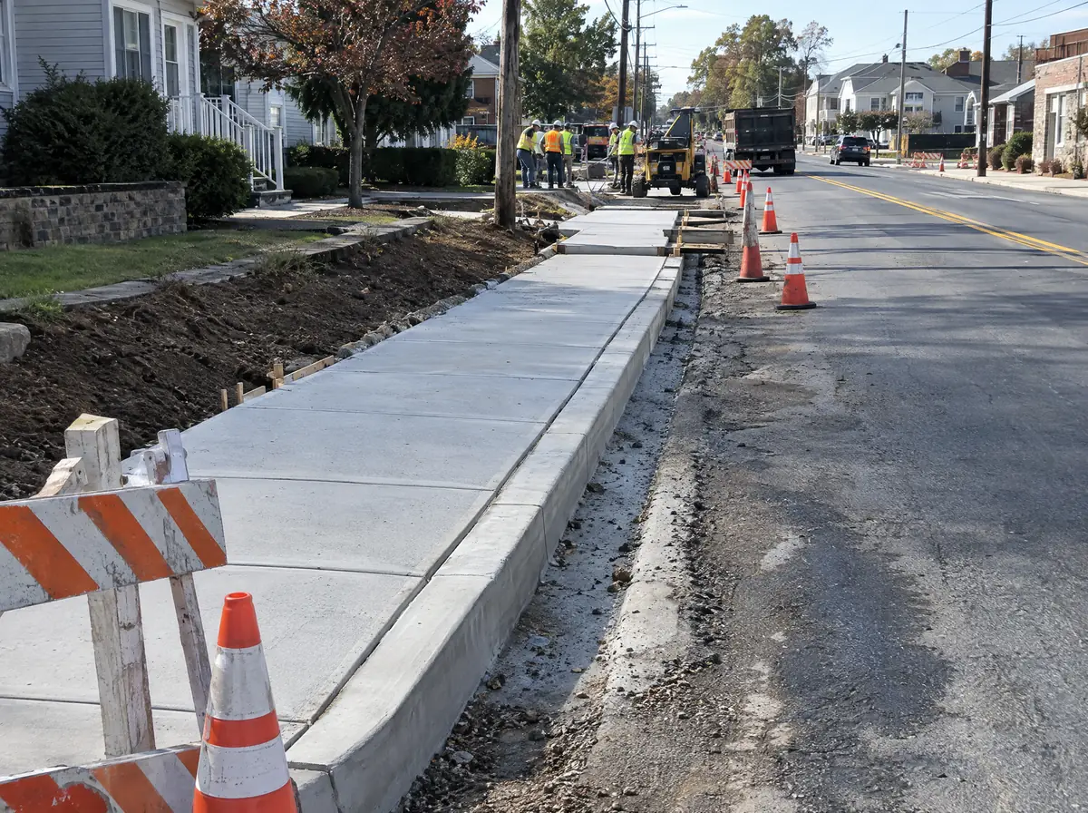 Municipal curb and sidewalk construction along a New Jersey main street with cones and barricades