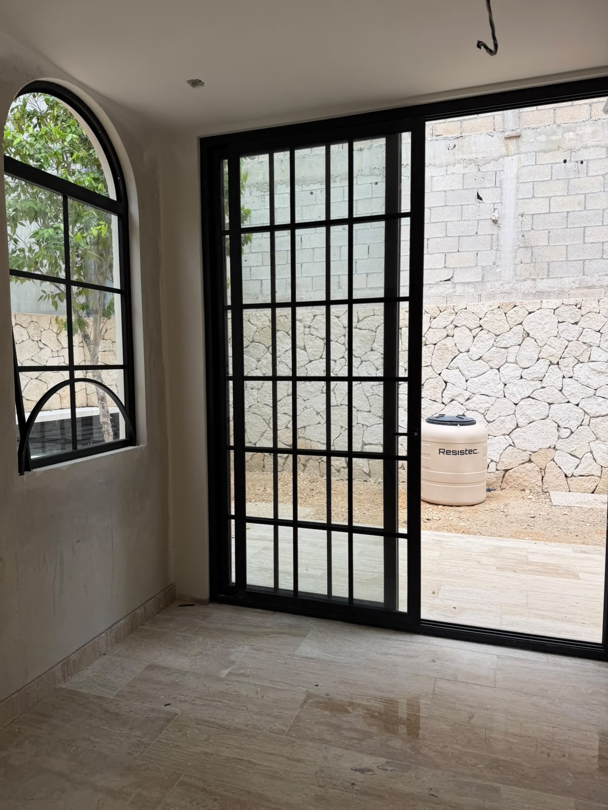 Custom black steel French doors and arched window overlooking the limestone patio