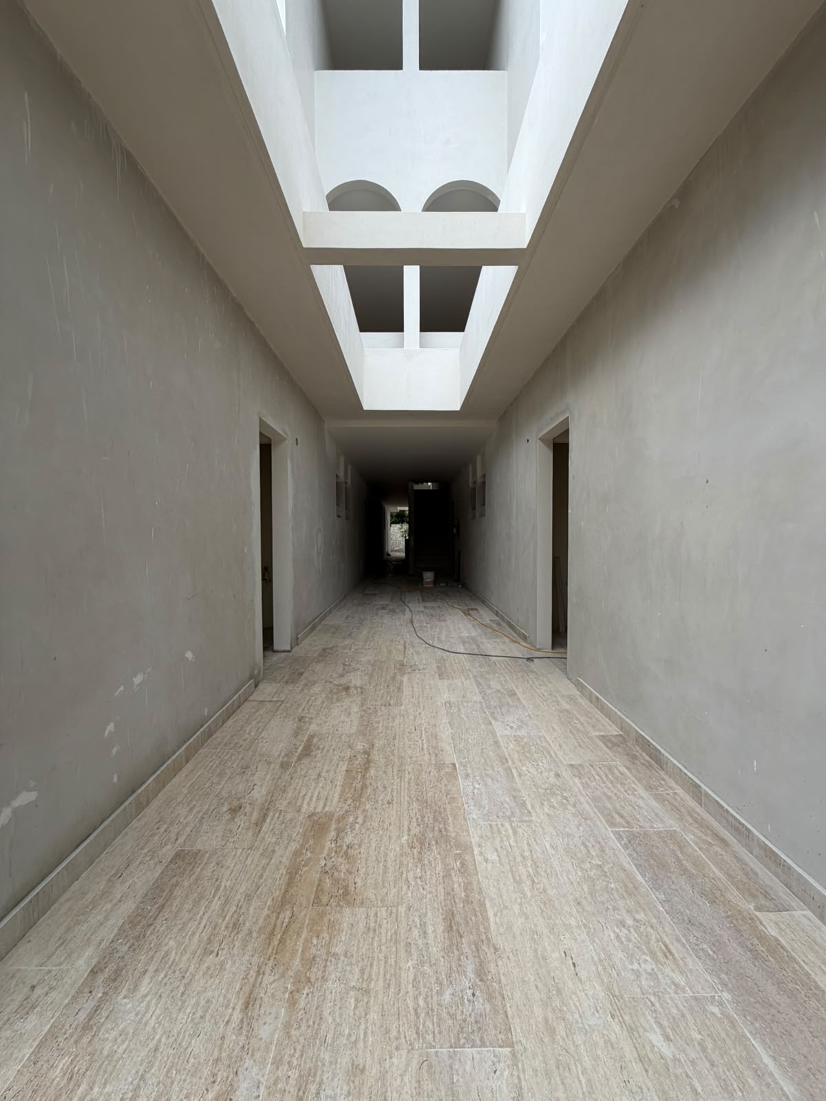 Central skylit gallery corridor with travertine flooring and arched portals