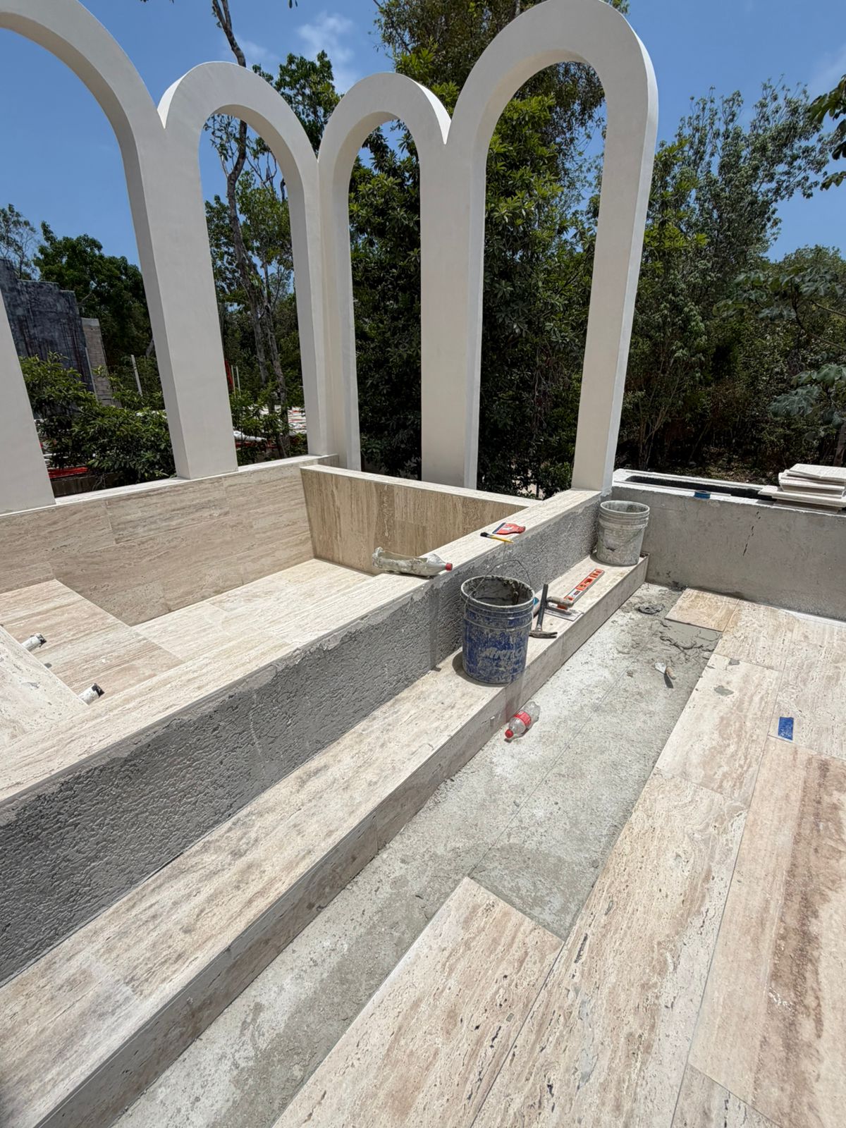 Rooftop plunge pool with Mediterranean arches and travertine stone cladding