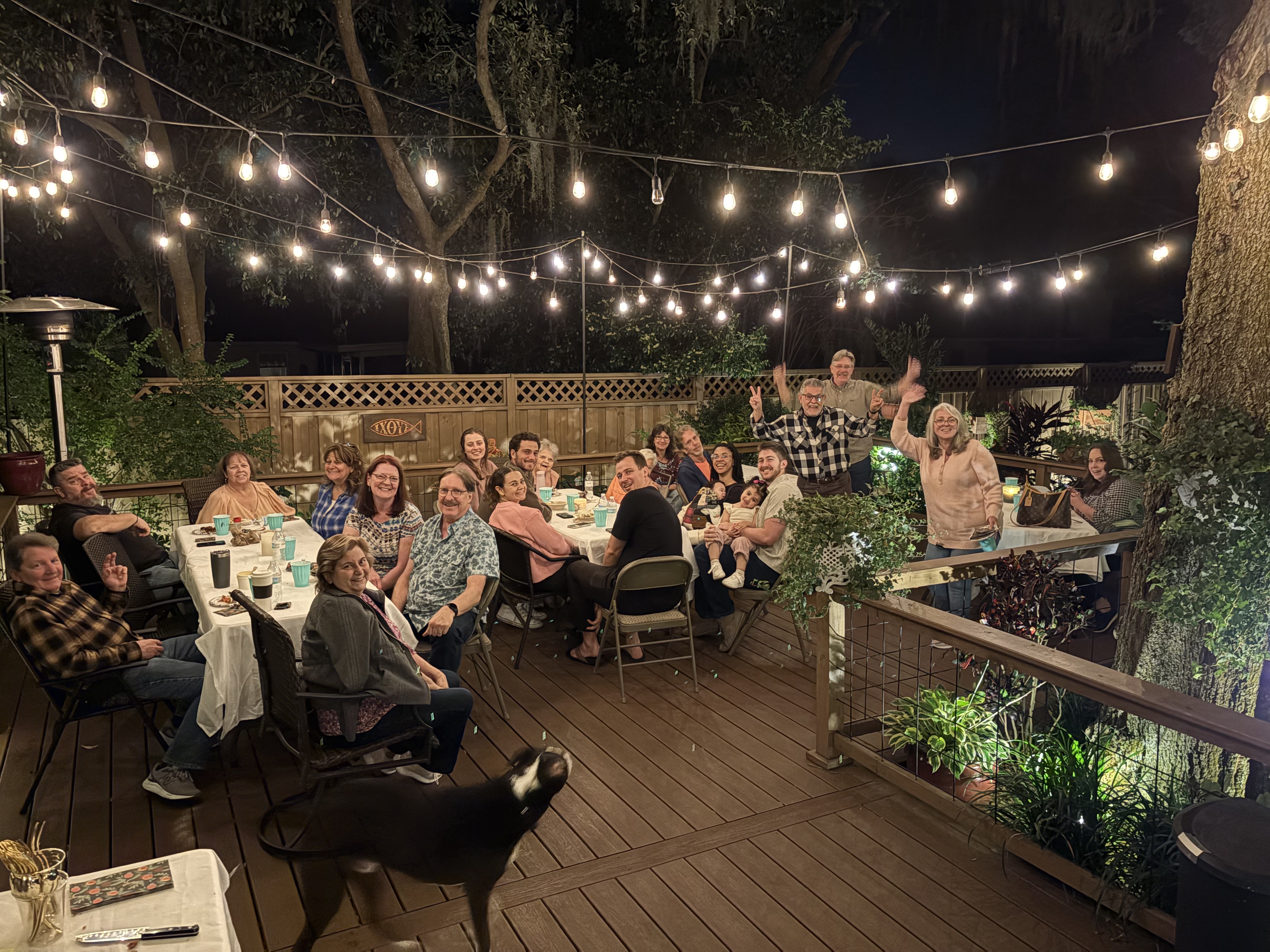 Community fellowship dinner and celebration around tables under the glowing string lights