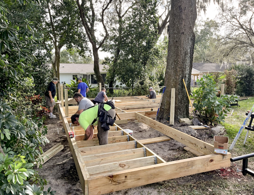 Men working together framing the wooden deck around the base of the shade tree