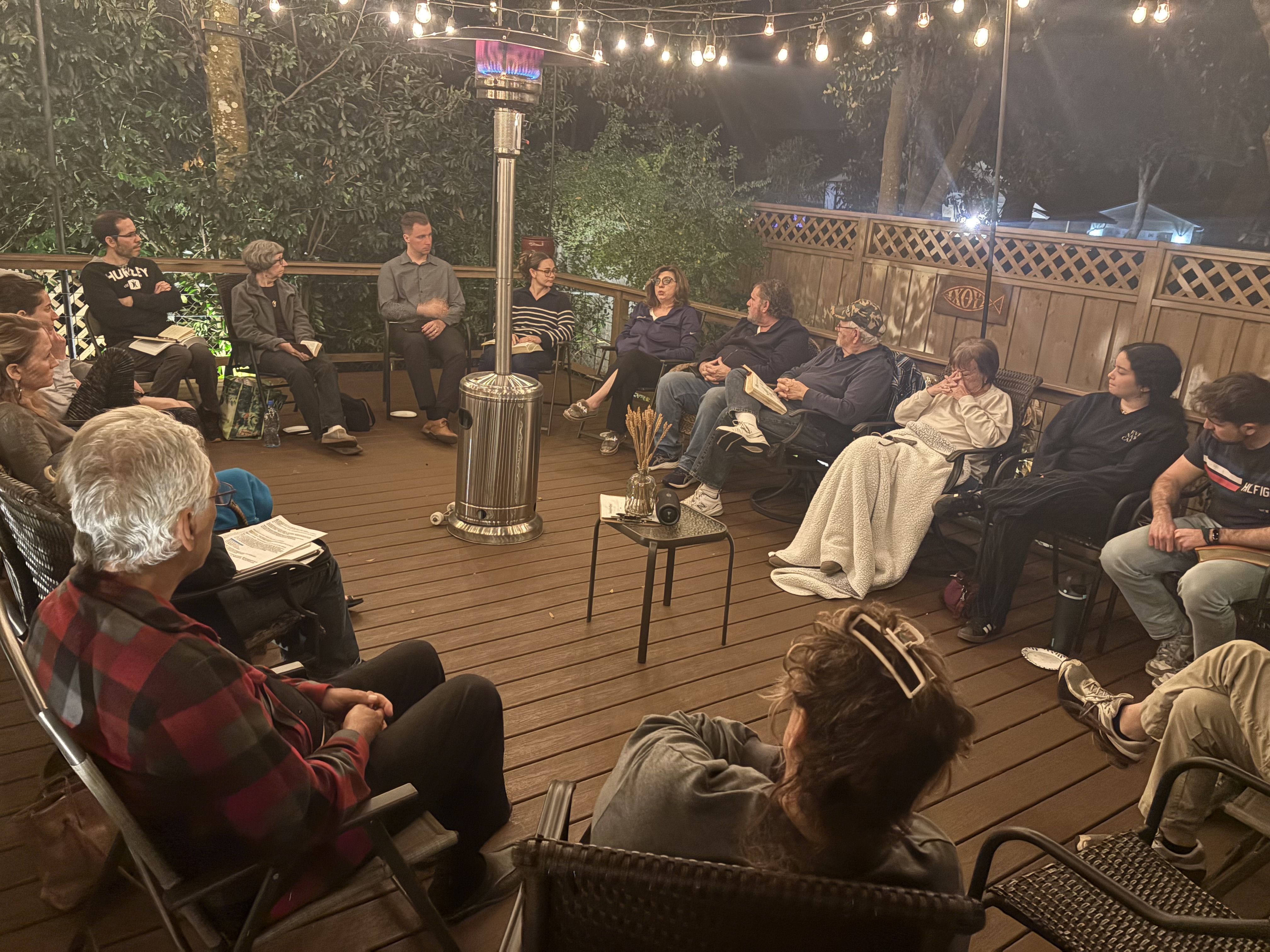Circle of believers gathered under string lights with patio heater and honest conversation