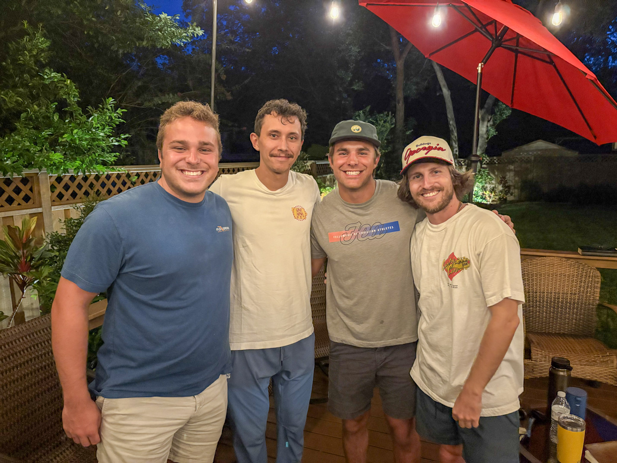Young men smiling warmly together on the deck after the gathering