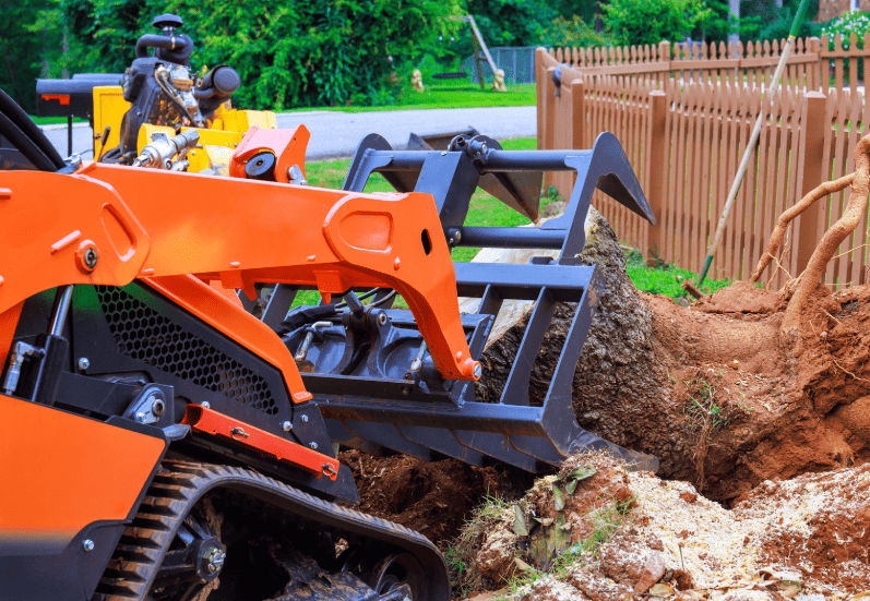 Compact track loader moving large tree stump and root ball in Castle Hill