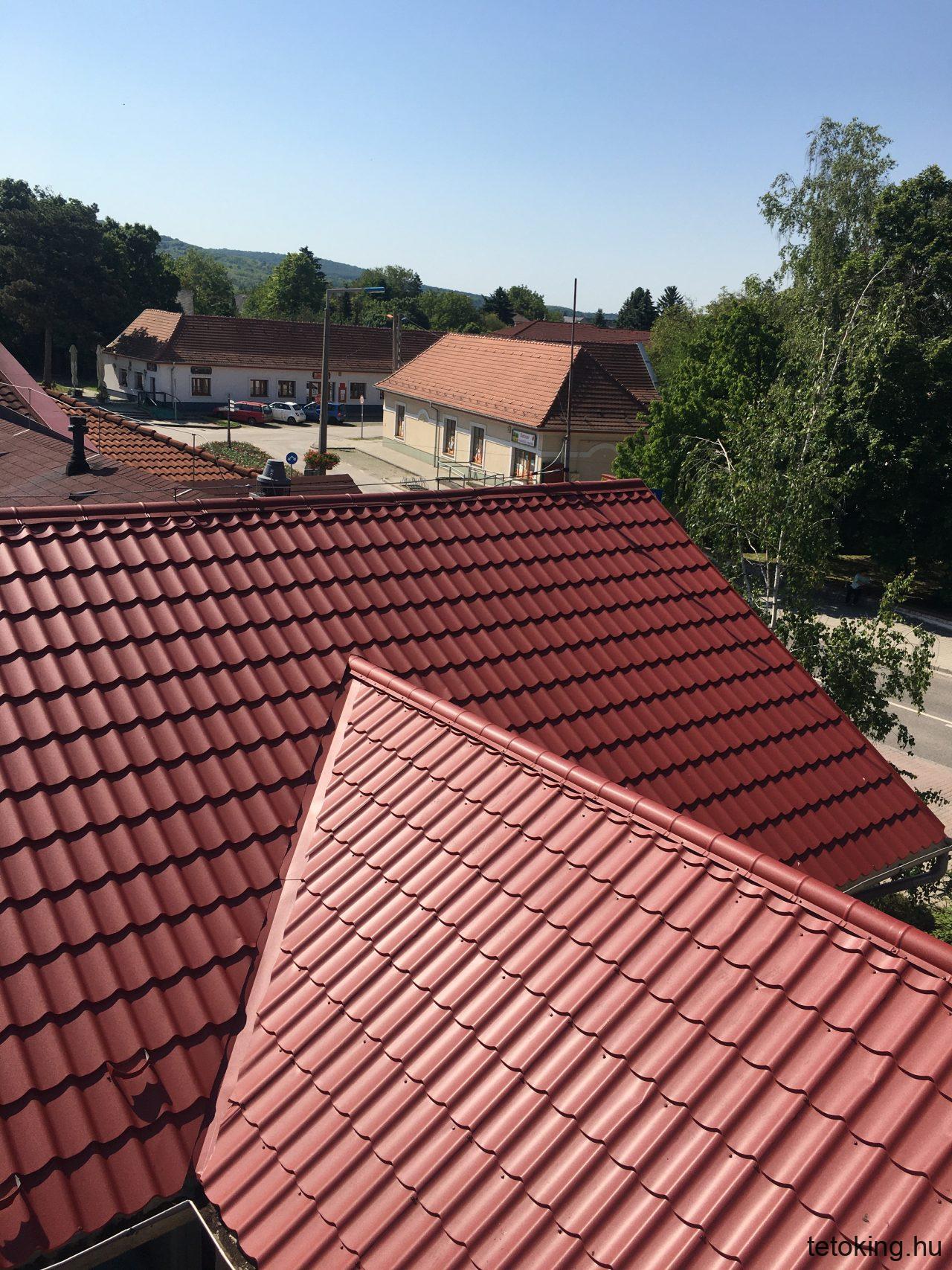 Pogled s ptičje perspektive na novo prekritje večkapne strehe z rdečo kovinsko kritino