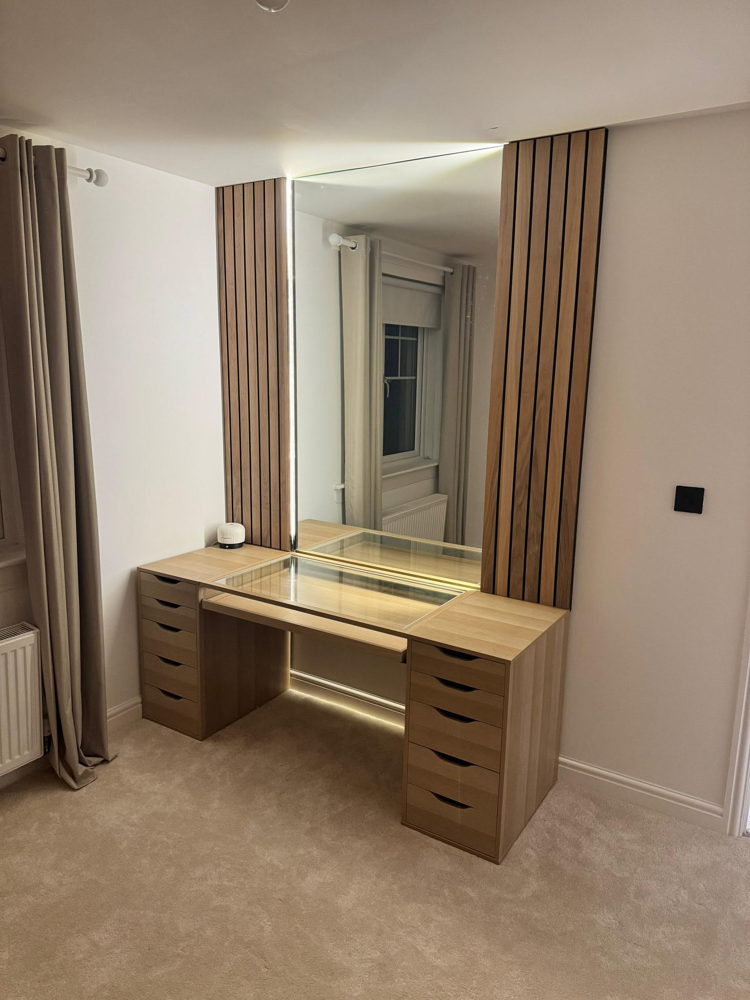 Custom oak dressing table with slatted timber acoustic panels, integrated backlit mirror and glass top by SJ Joinery & Building