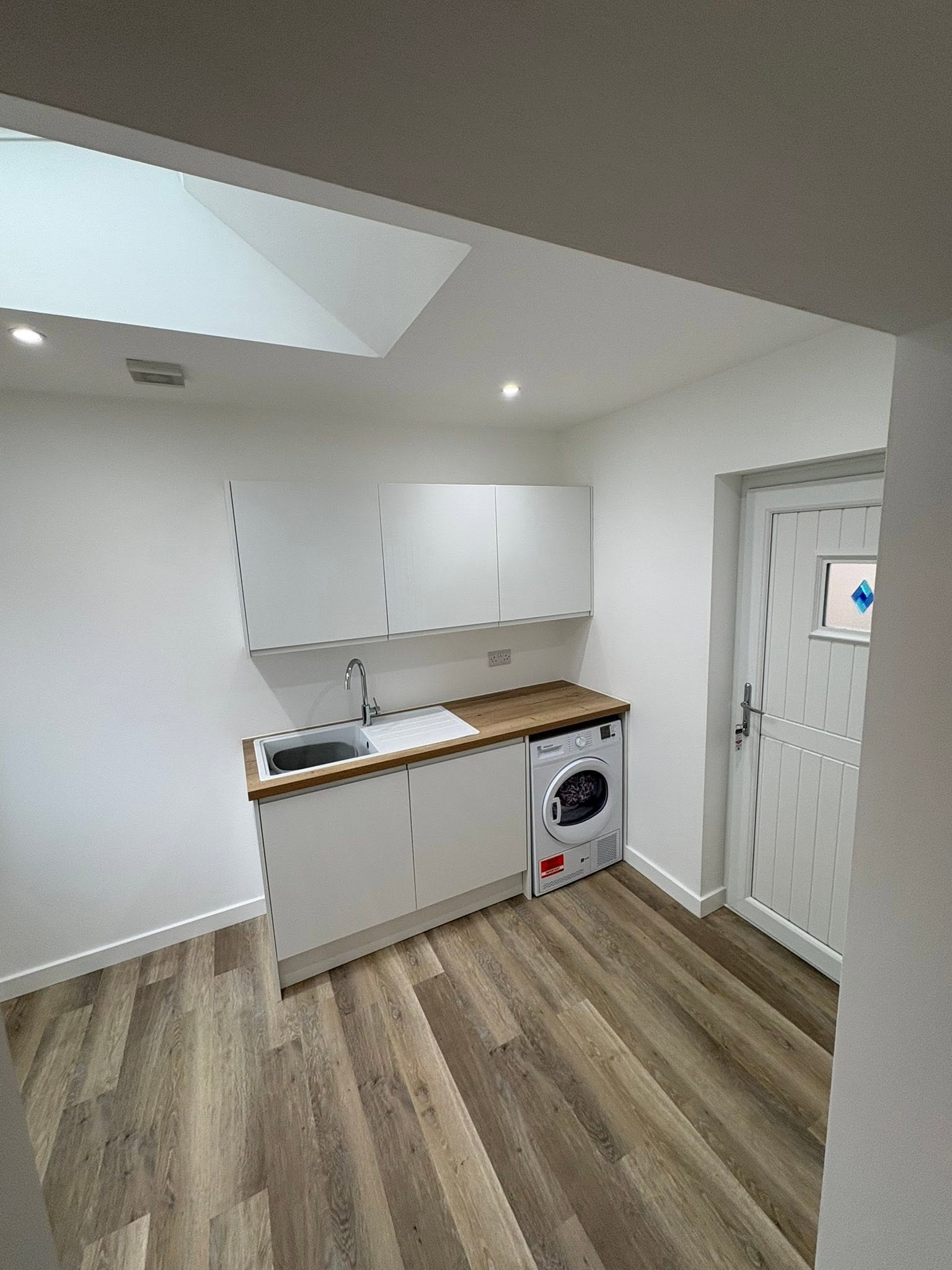 Bespoke fitted utility room with oak laminate worktop, modern cabinetry, laundry appliances and recessed skylight by SJ Joinery & Building