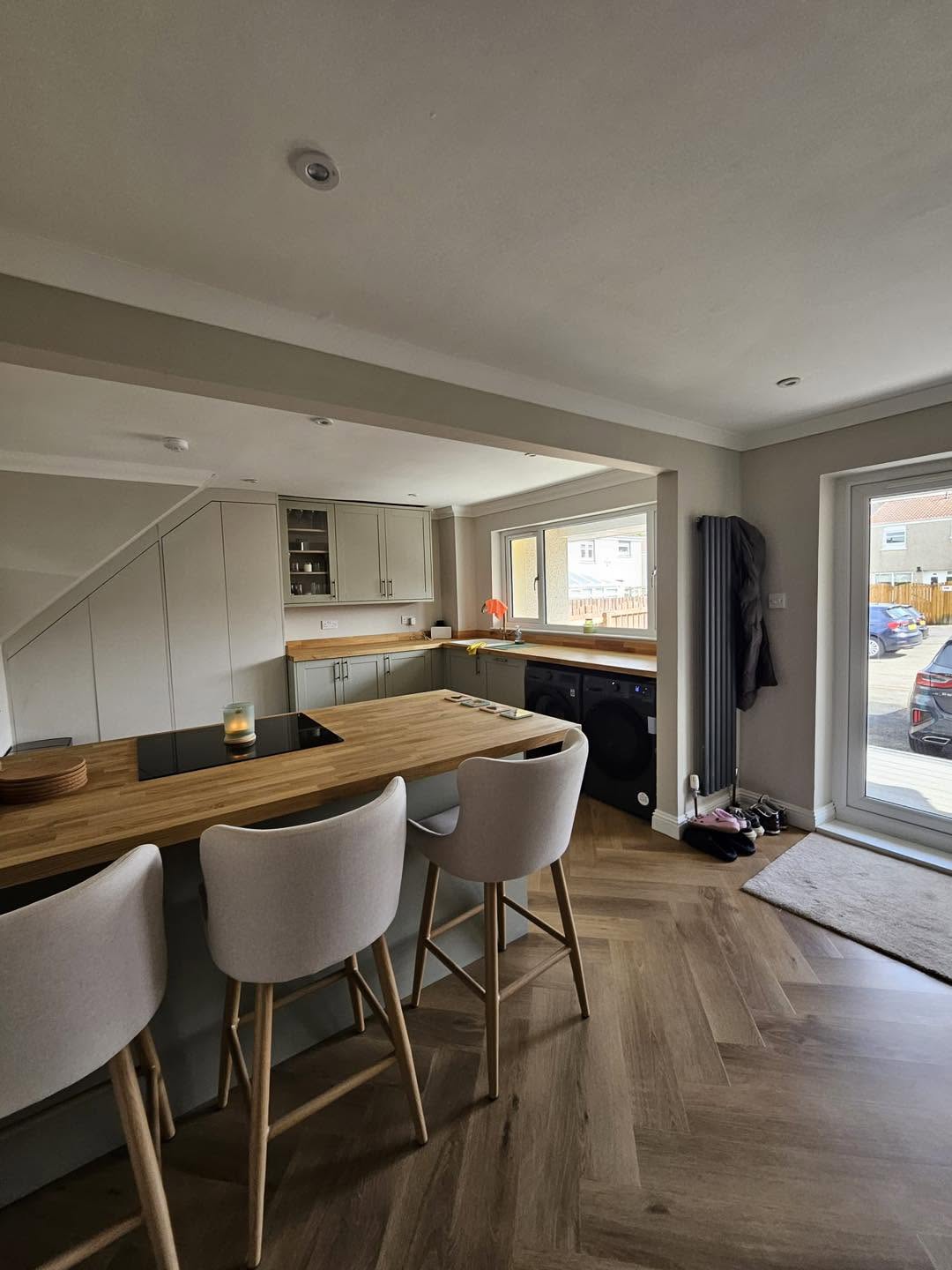 Open-plan kitchen renovation with bespoke breakfast bar island, solid oak worktops, under-stair storage and herringbone flooring by SJ Joinery & Building