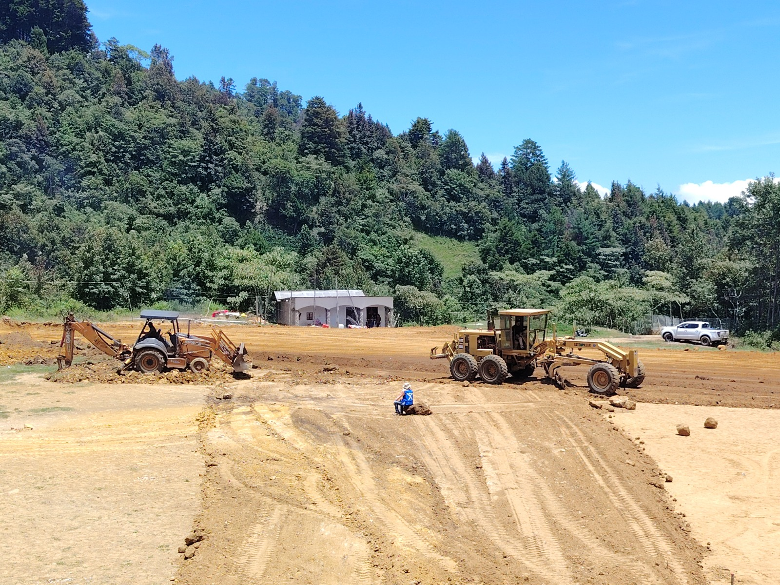 Movimiento de tierras, nivelación con motoniveladora y retroexcavadora en obra