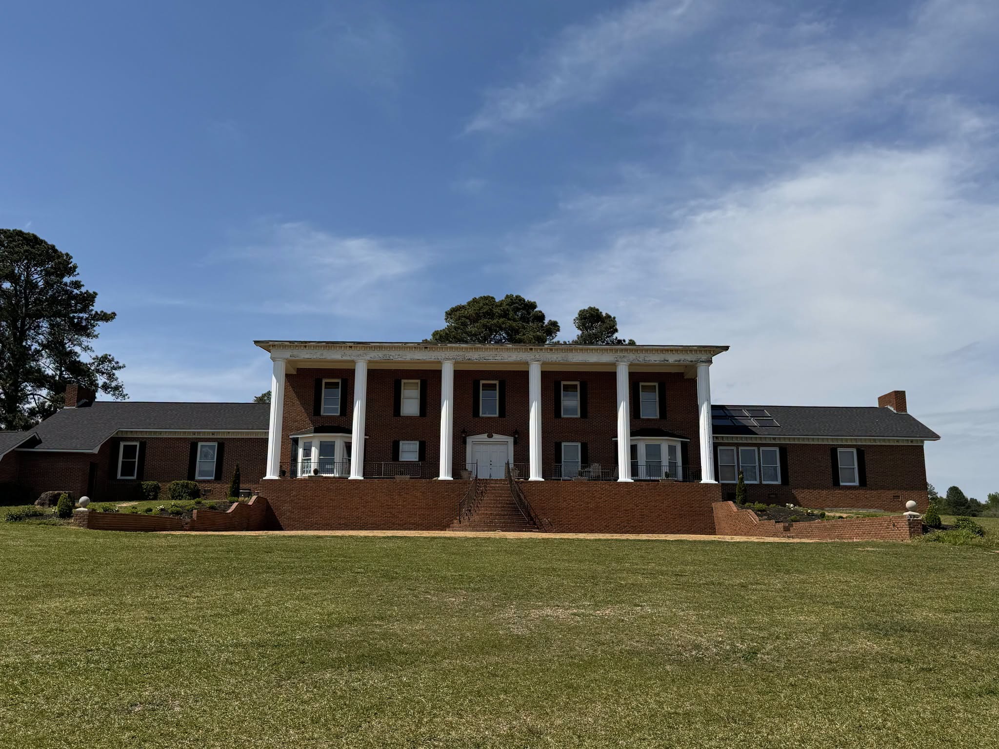 The Big House full Southern Colonial brick facade with grand columns and front lawn