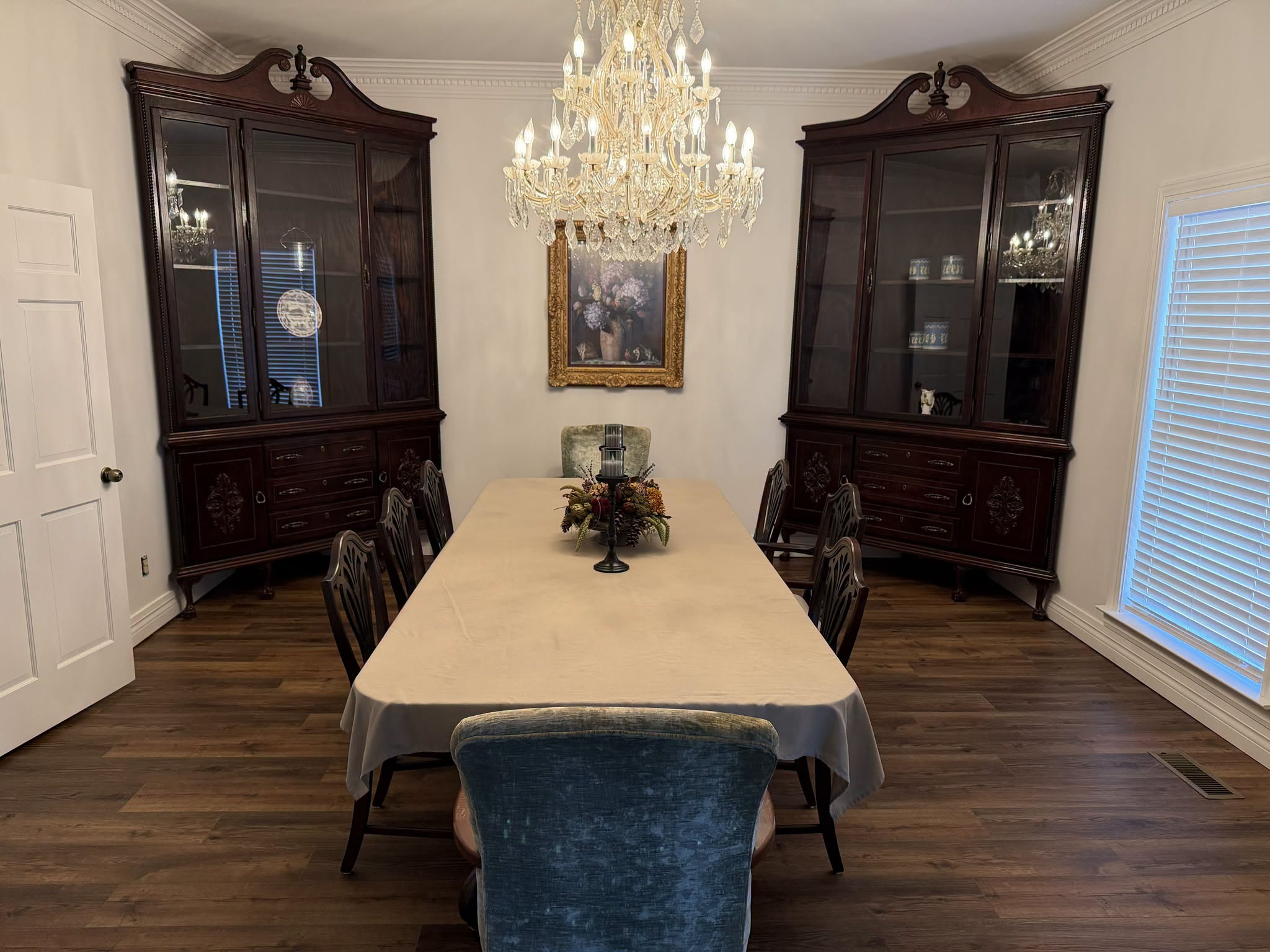Formal dining room with chandelier, long dining table, and antique china cabinets