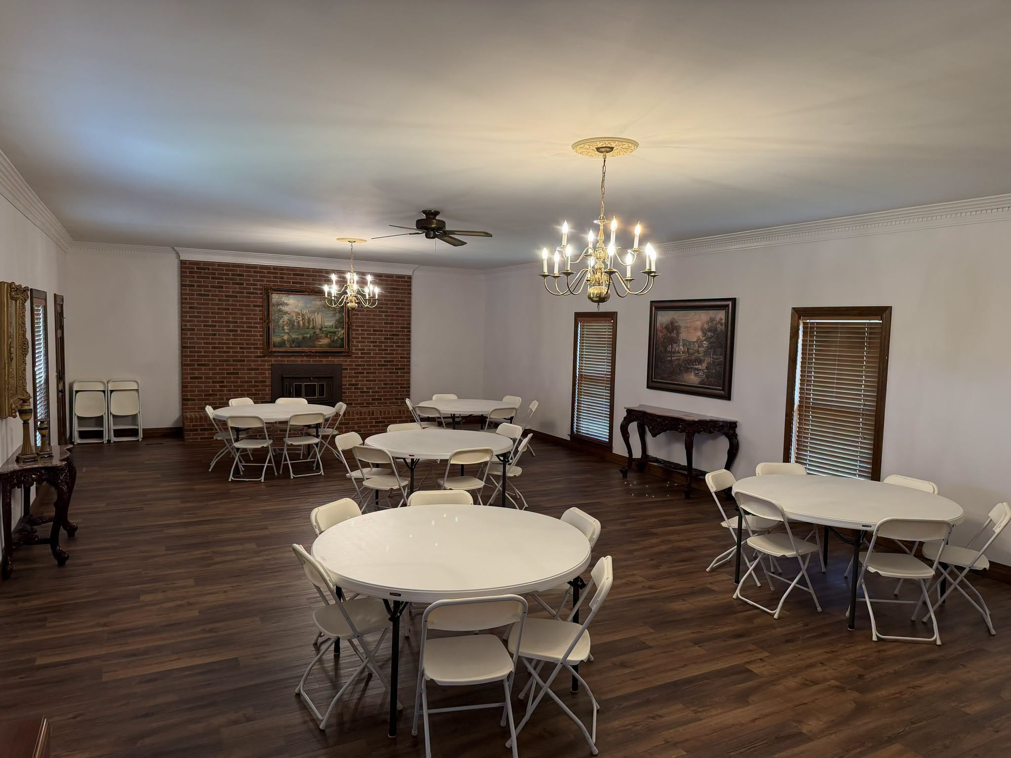 Spacious downstairs gathering room with round tables, fireplace, and chandeliers