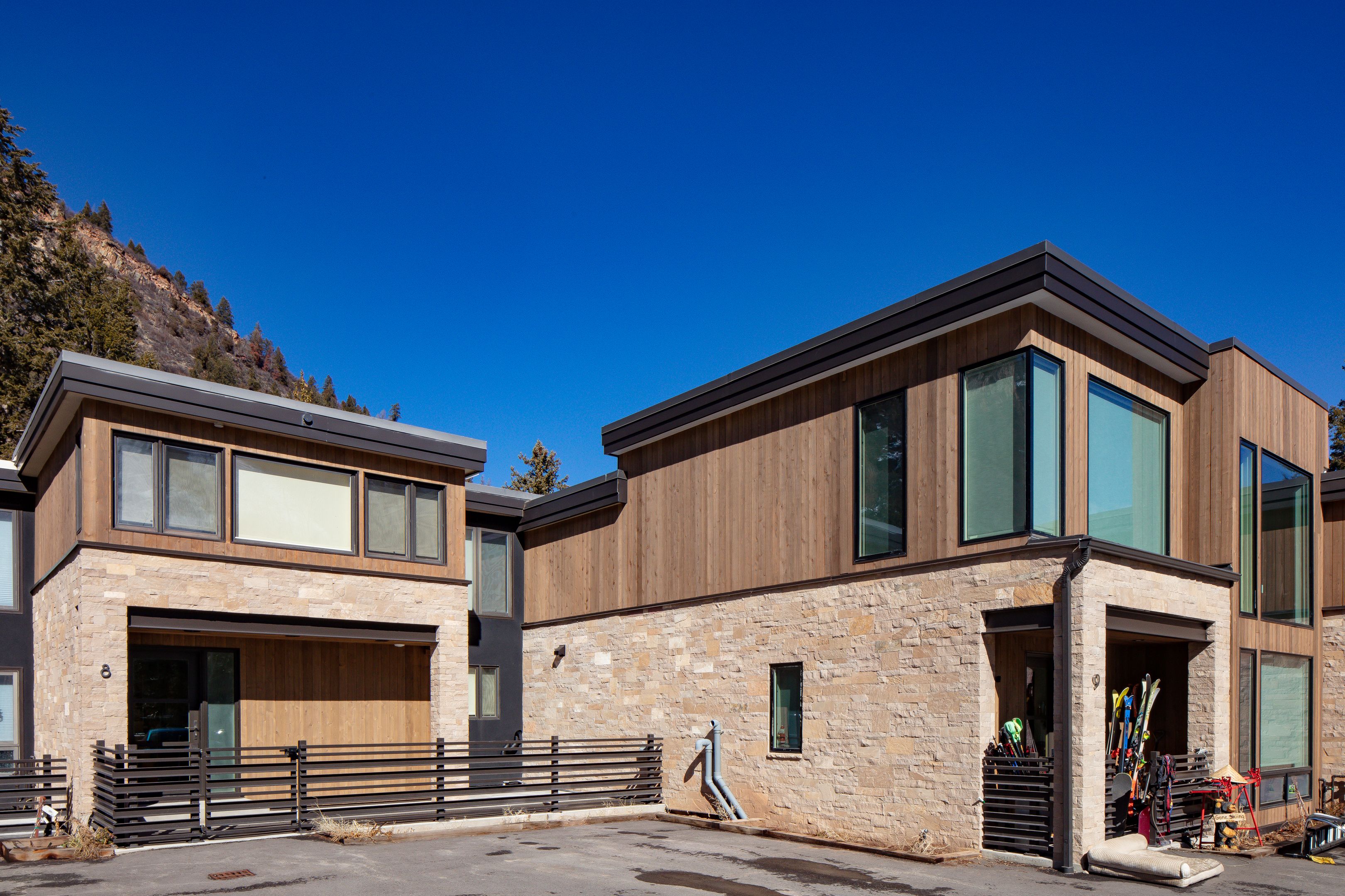 Corner glazing and stone facade with ski storage along the lower alpine courtyard — Highlands Villas, Aspen, CO