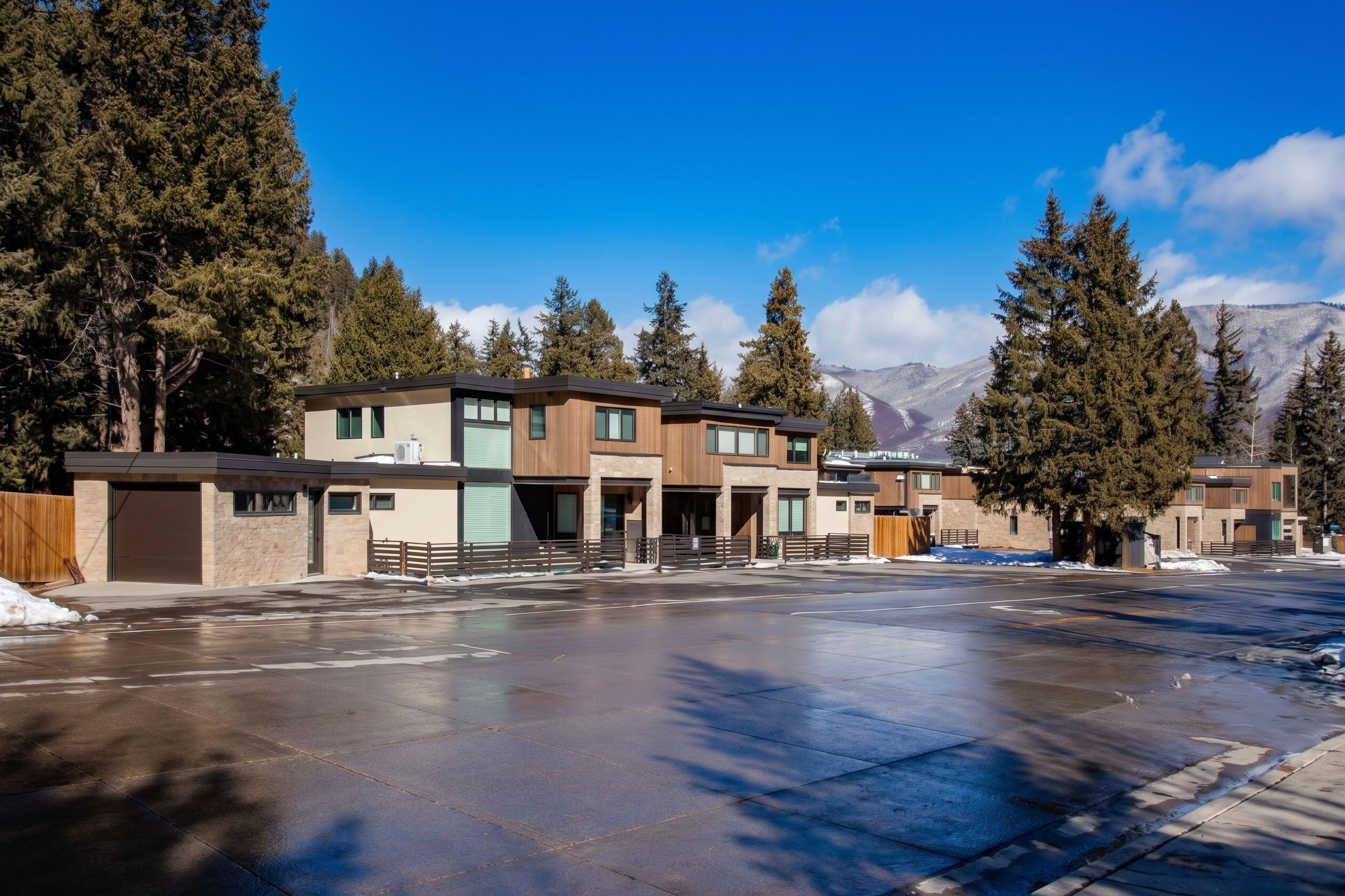 Wide exterior view of modern mountain townhomes and alpine ridgeline across clear courtyard — Highlands Villas, Aspen, CO