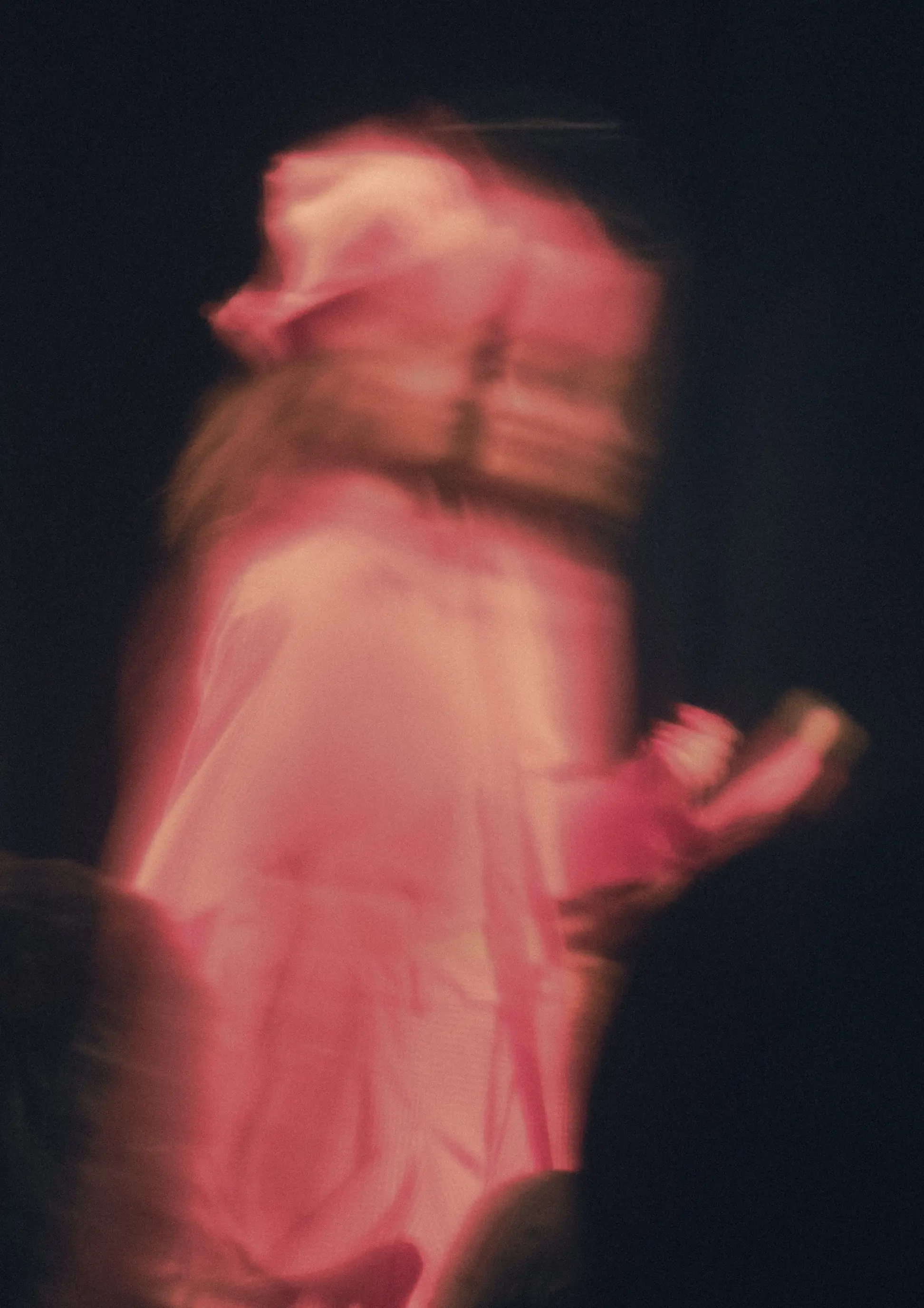 Motion blur portrait with luminous coral pink light and ethereal draped silhouette