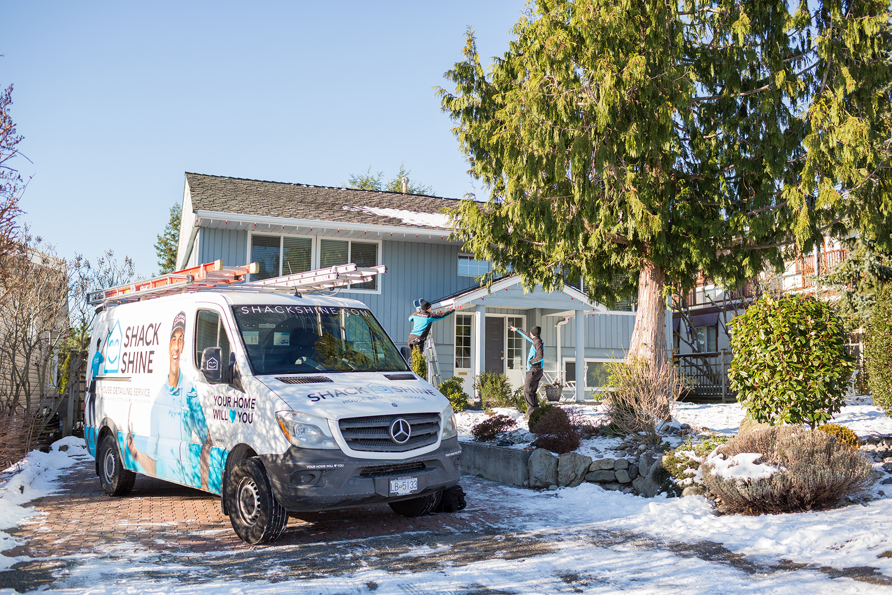 Shack Shine branded service van and uniformed technicians preparing exterior home service in winter