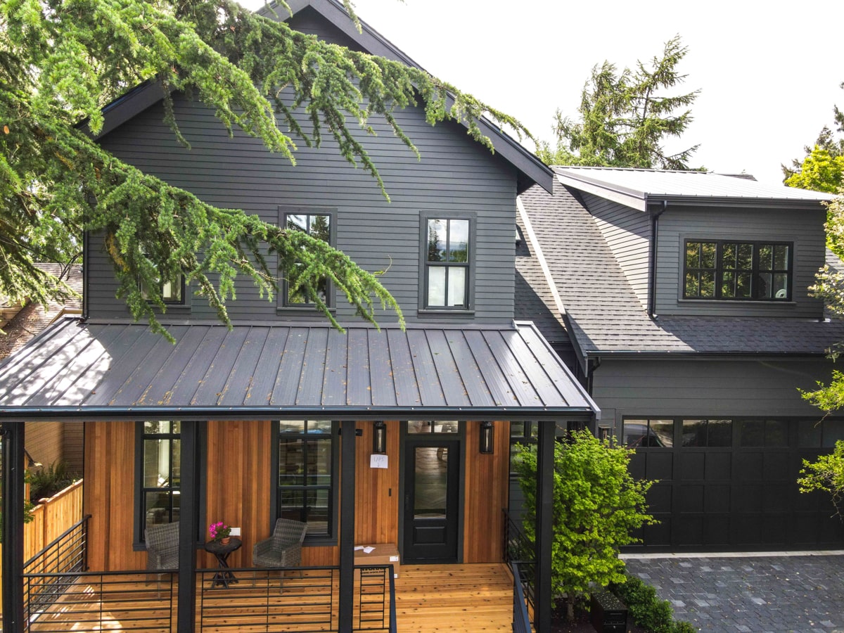 Elevated front view of standing seam metal porch roof, upper gabled dormer, and natural pine entry siding