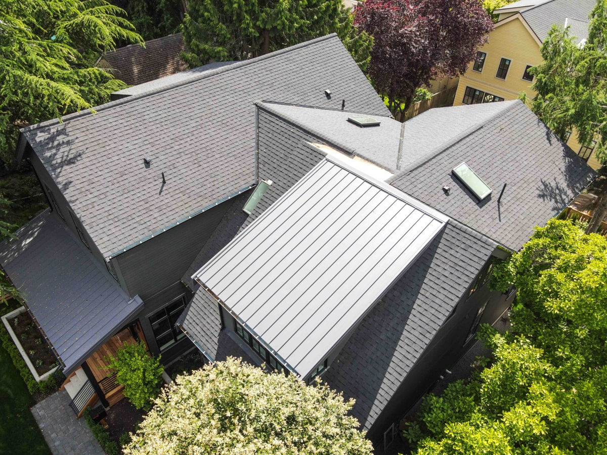 Standing seam metal roof installation next to architectural shingle roofing in Seattle WA by Best Quality