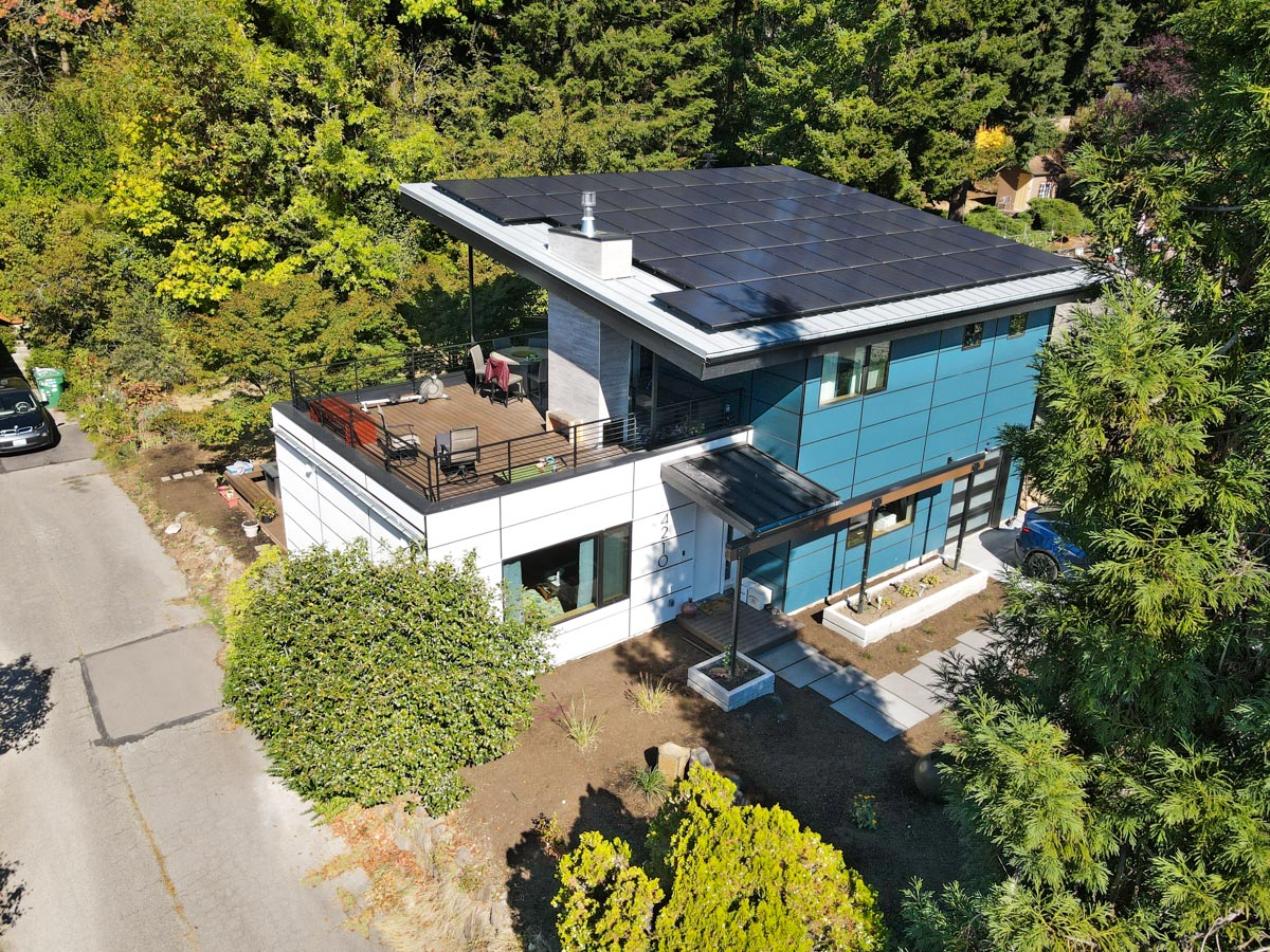 Aerial perspective of modern two-story home rebuild featuring the 16KW rooftop solar array and upper wood deck