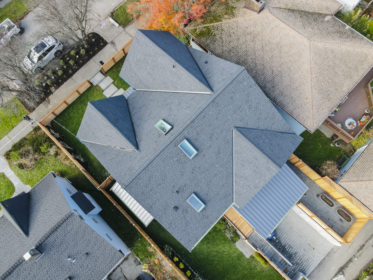 Direct overhead aerial view of charcoal architectural shingle roof layout, skylights, and standing seam metal patio cover