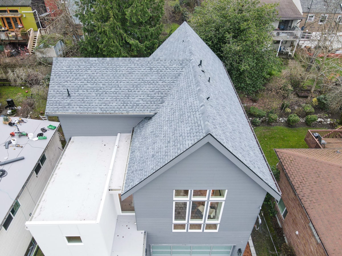 Aerial view of steep architectural shingle roof over blue Hardie lap siding in Seattle WA