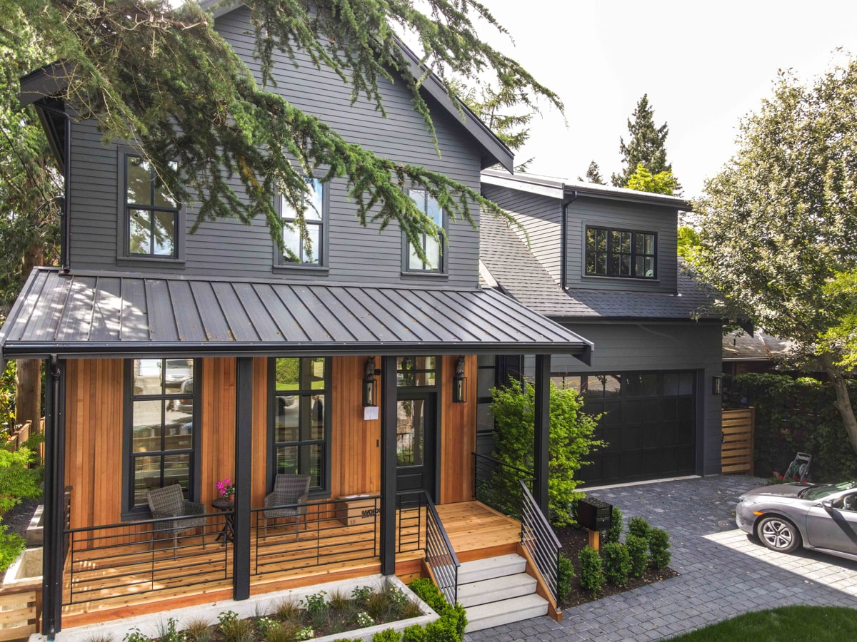 Front view of cabin style Seattle home with standing seam metal porch roof, fiber cement siding and natural pine paneling