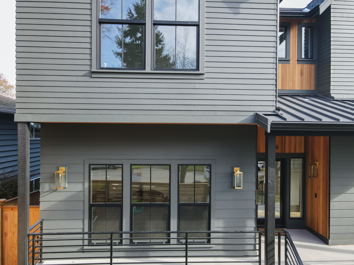 Porch and exterior detail highlighting James Hardie lap siding, black railings, modern exterior sconces, and cedar entry accents