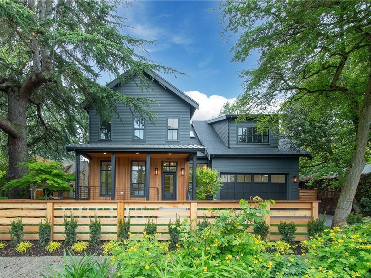 Street-level landscaped view of modern rustic Seattle home framed by cedar fencing and lush greenery