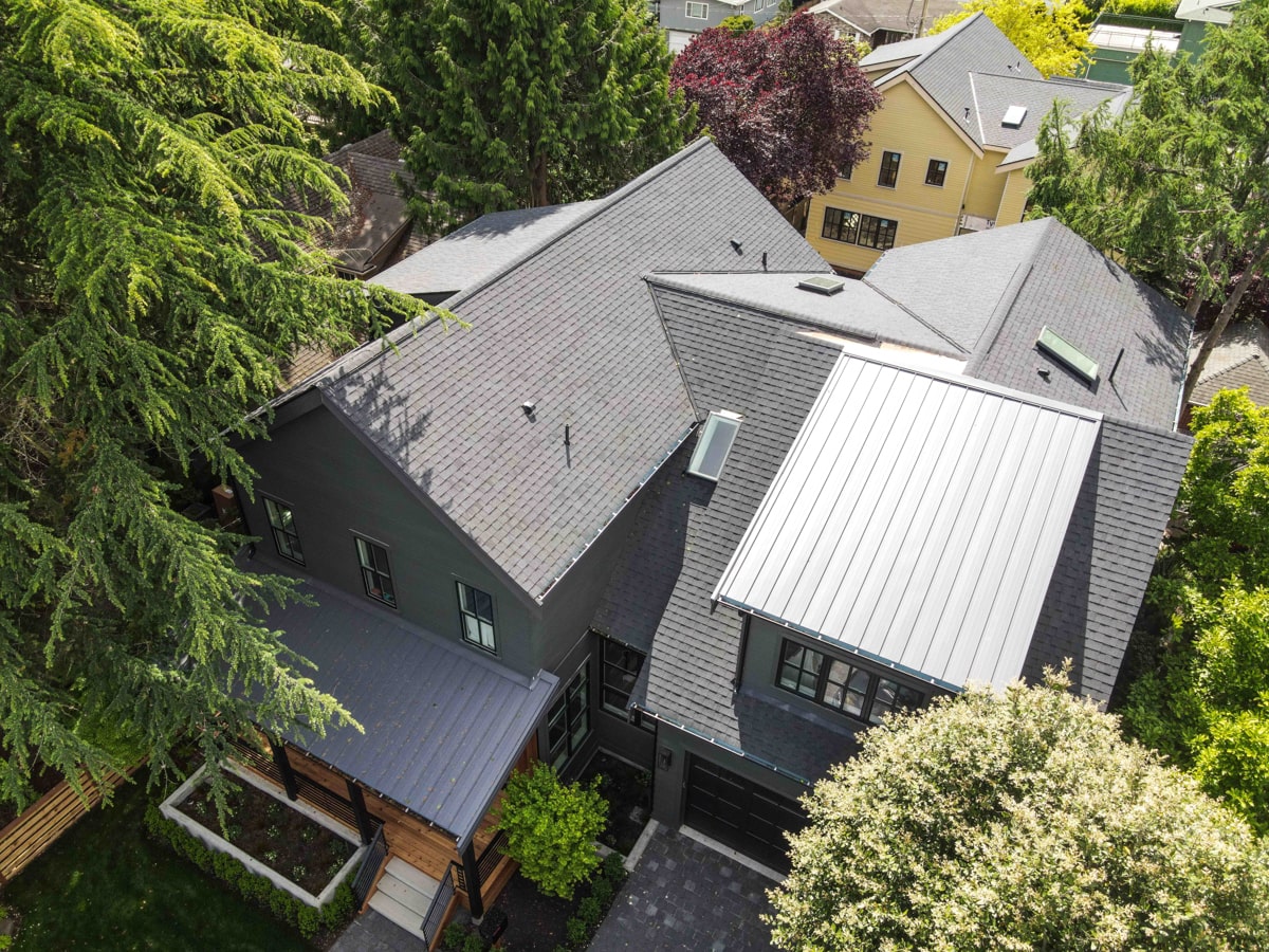 Aerial view of architectural shingle roof and standing seam metal roof sections on a Seattle WA home
