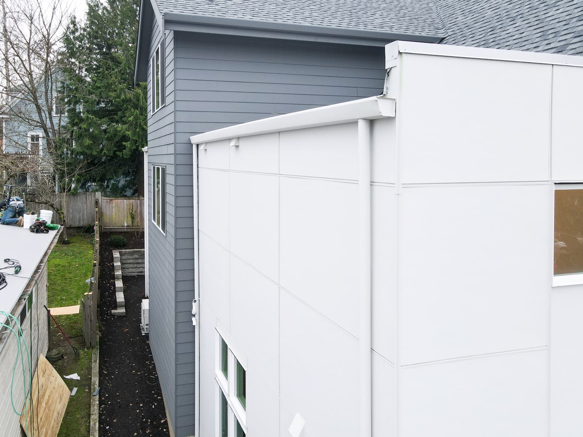Side perspective showing transition between white panel siding tower and muted blue Hardie lap siding wall
