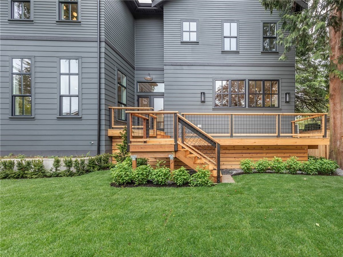 Rear exterior elevation showing custom cedar deck, steel wire railings, and charcoal James Hardie siding