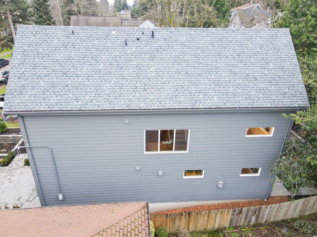 Full side elevation showing muted blue lap siding and symmetrical architectural shingle roof slope in Seattle WA