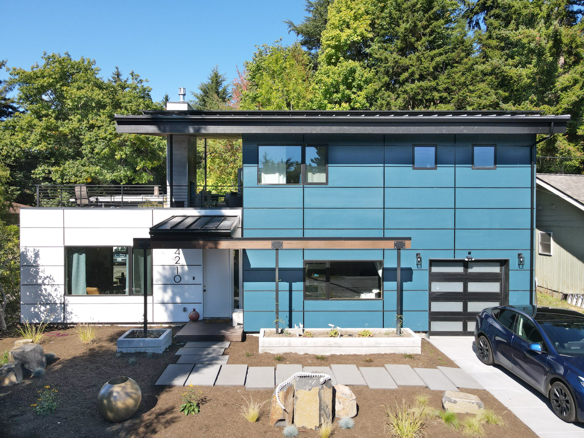 Crisp straight-on view of the two-story rebuild with smoky blue panels, vanilla milkshake siding, and modern front deck