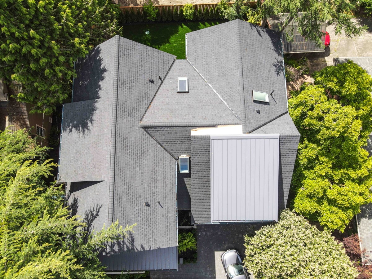 Overhead aerial view of architectural shingle roof layout, skylights, and standing seam metal roof accents