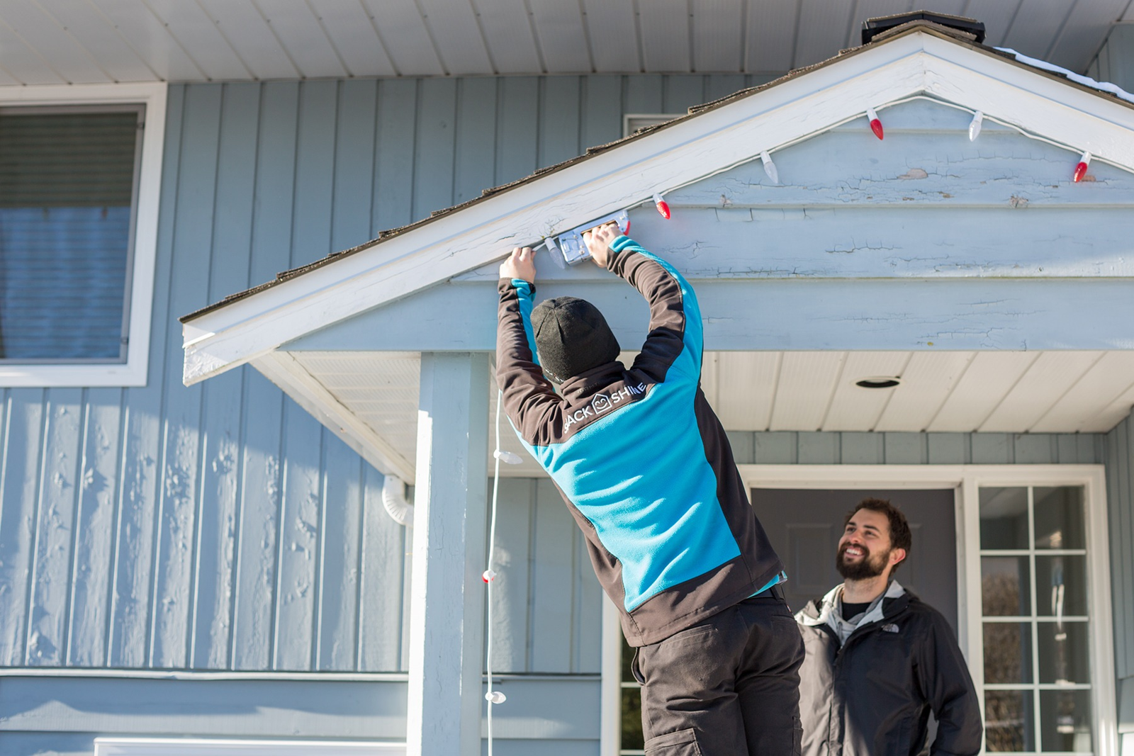 Uniformed Shack Shine technicians carefully installing custom-cut roofline Christmas lights
