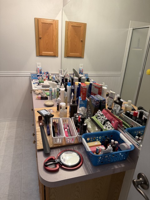 Bathroom vanity counter with personal care products, hair tools, and organizer baskets