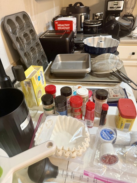 Kitchen counter assortment with spices, coffee filters, baking pans, and small appliances
