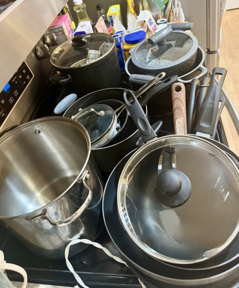 Stack of nonstick and stainless steel cookware, pots, and pans with glass lids