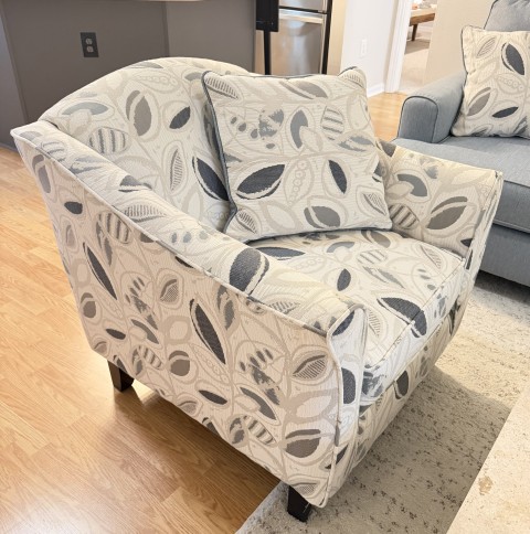 Upholstered accent armchair with leaf pattern fabric and matching throw pillow