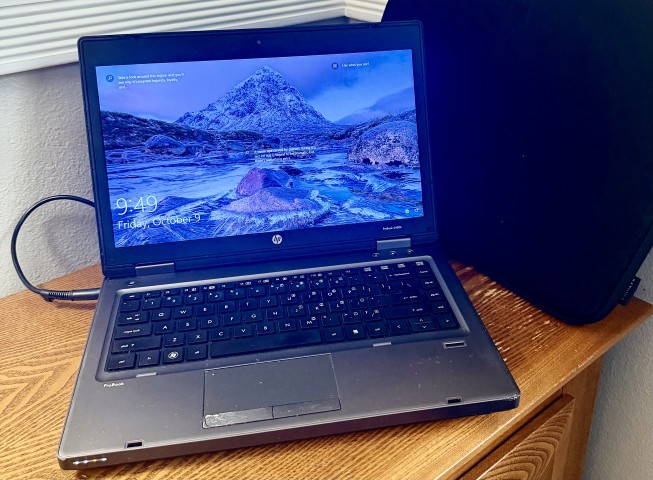 HP ProBook laptop computer open on wood nightstand