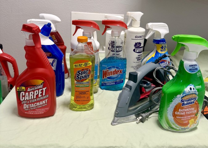 Household cleaning supplies including carpet stain remover, Windex, and clothing iron