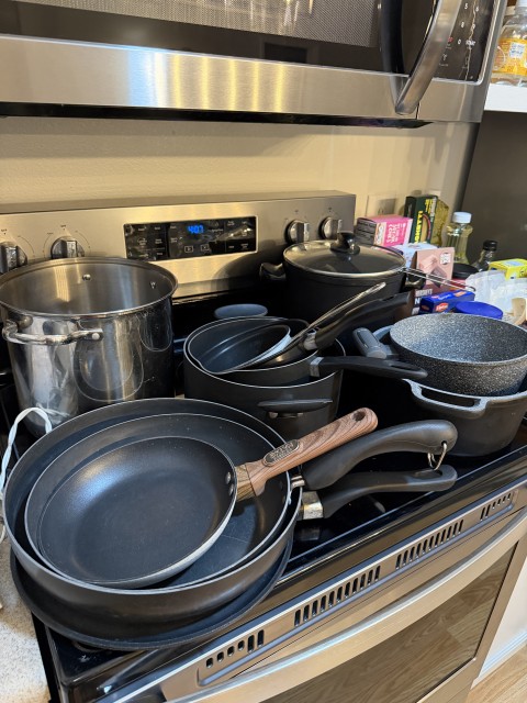 Assortment of nonstick frying pans, saucepans, and stainless stock pot on stovetop