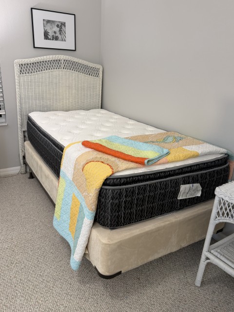 Twin bed with white wicker headboard, mattress, and decorative quilt
