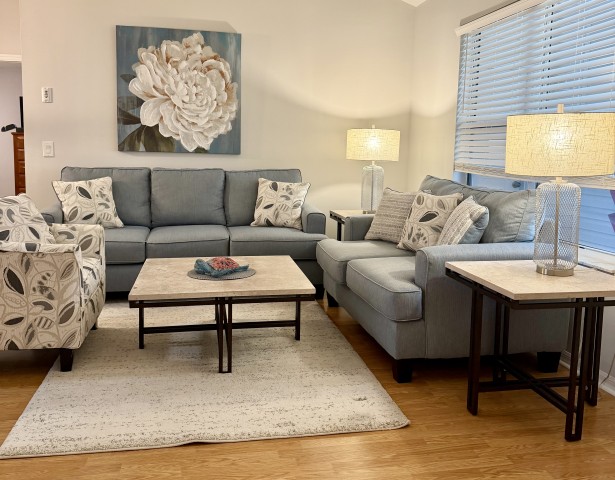 Complete living room set with blue sofas, patterned armchair, stone coffee and side tables, and lamps