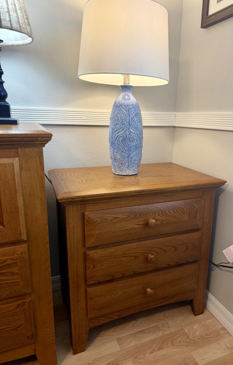 Solid oak three-drawer nightstand with blue ceramic table lamp