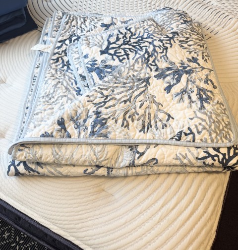 Folded coastal blue coral and sea life quilted throw blanket
