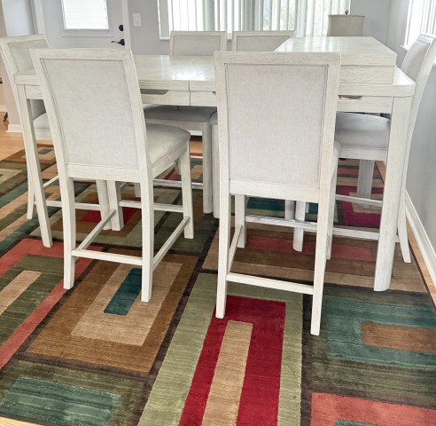 High-top counter height dining table set with upholstered barstools on geometric area rug
