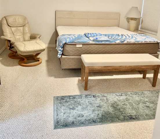Master bedroom suite with king bed, leather swivel recliner with ottoman, and upholstered bench