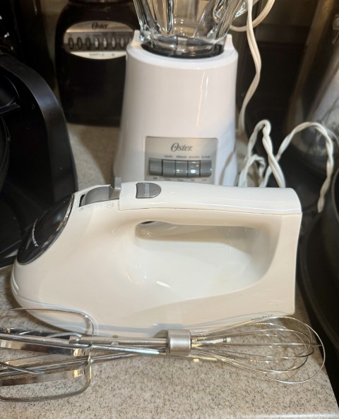 White electric hand mixer with beaters and whisk attachments